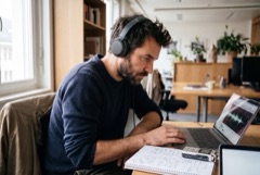 A journalist wearing headphones works on an interview recording.